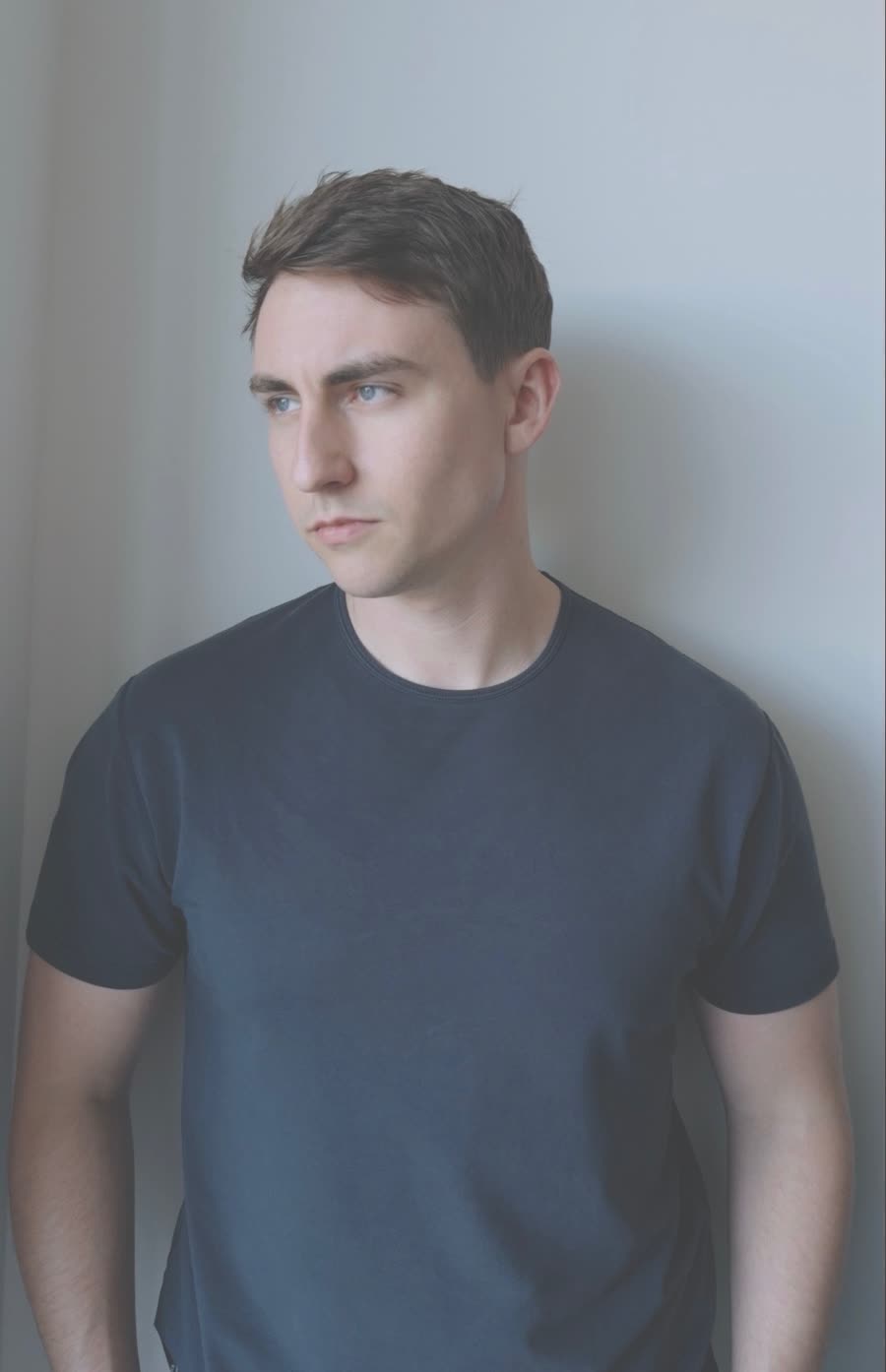 Justin Tate of Starfell against a pale wall, looking off to the side